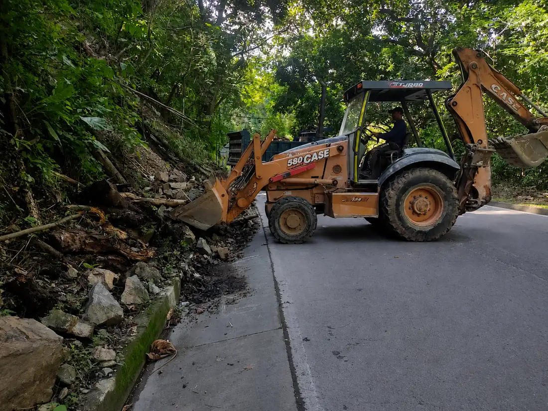 Retroexcavadora retirando el material de un derrumbe sobre una vía nacional